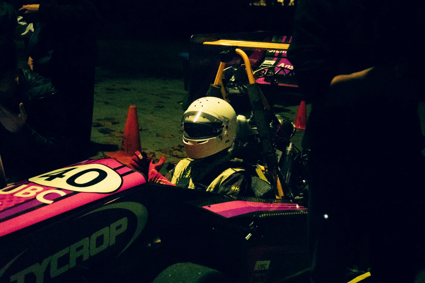 Nathan in a yellow helmet in the cockpit of the 2026 car at night